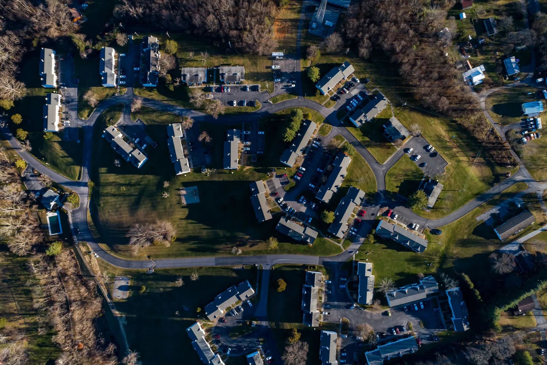 Aerial view of a residential neighborhood with multi-unit buildings, roads, trees, and grassy areas.
