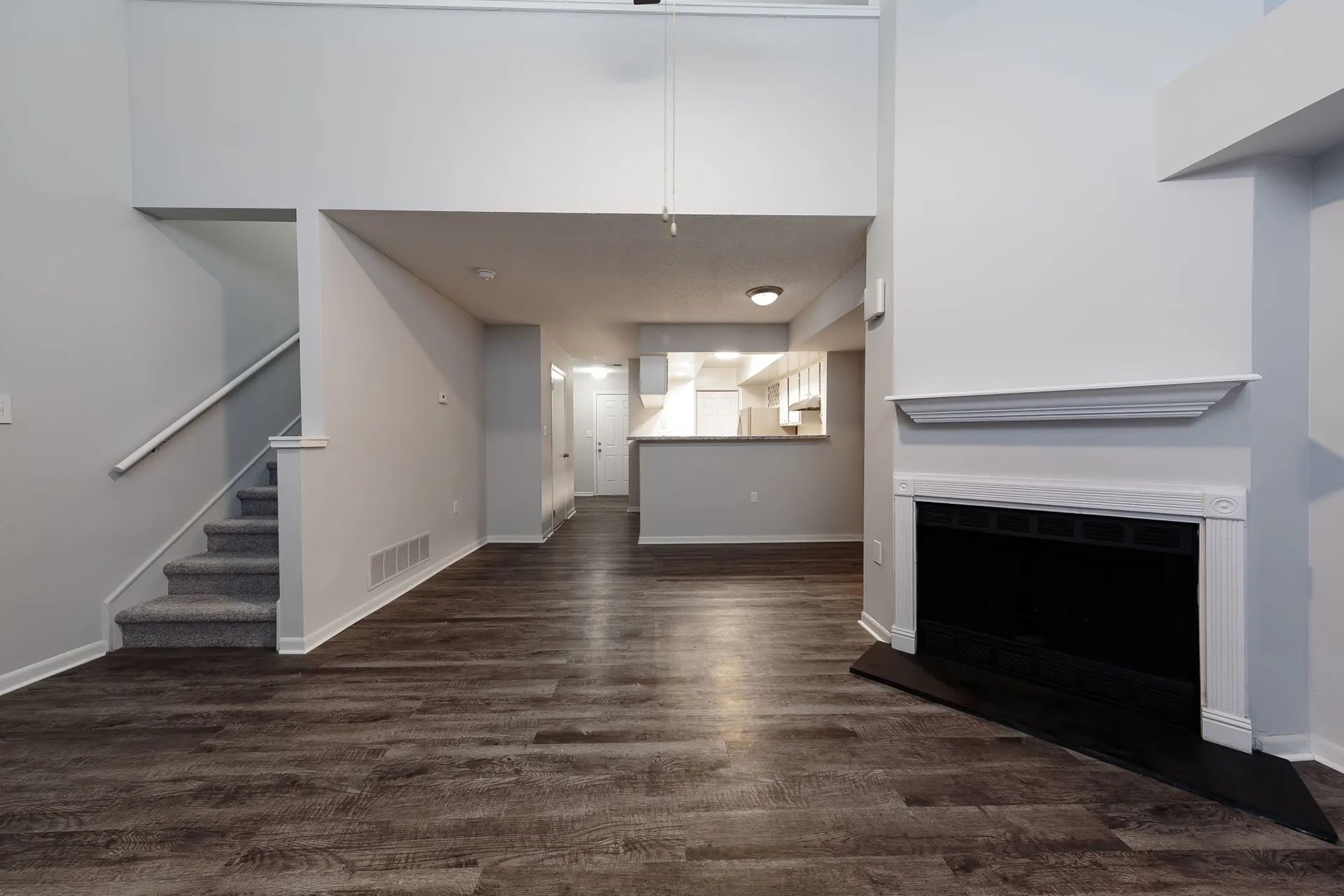 Open living space with stairs, fireplace, and view of kitchen.