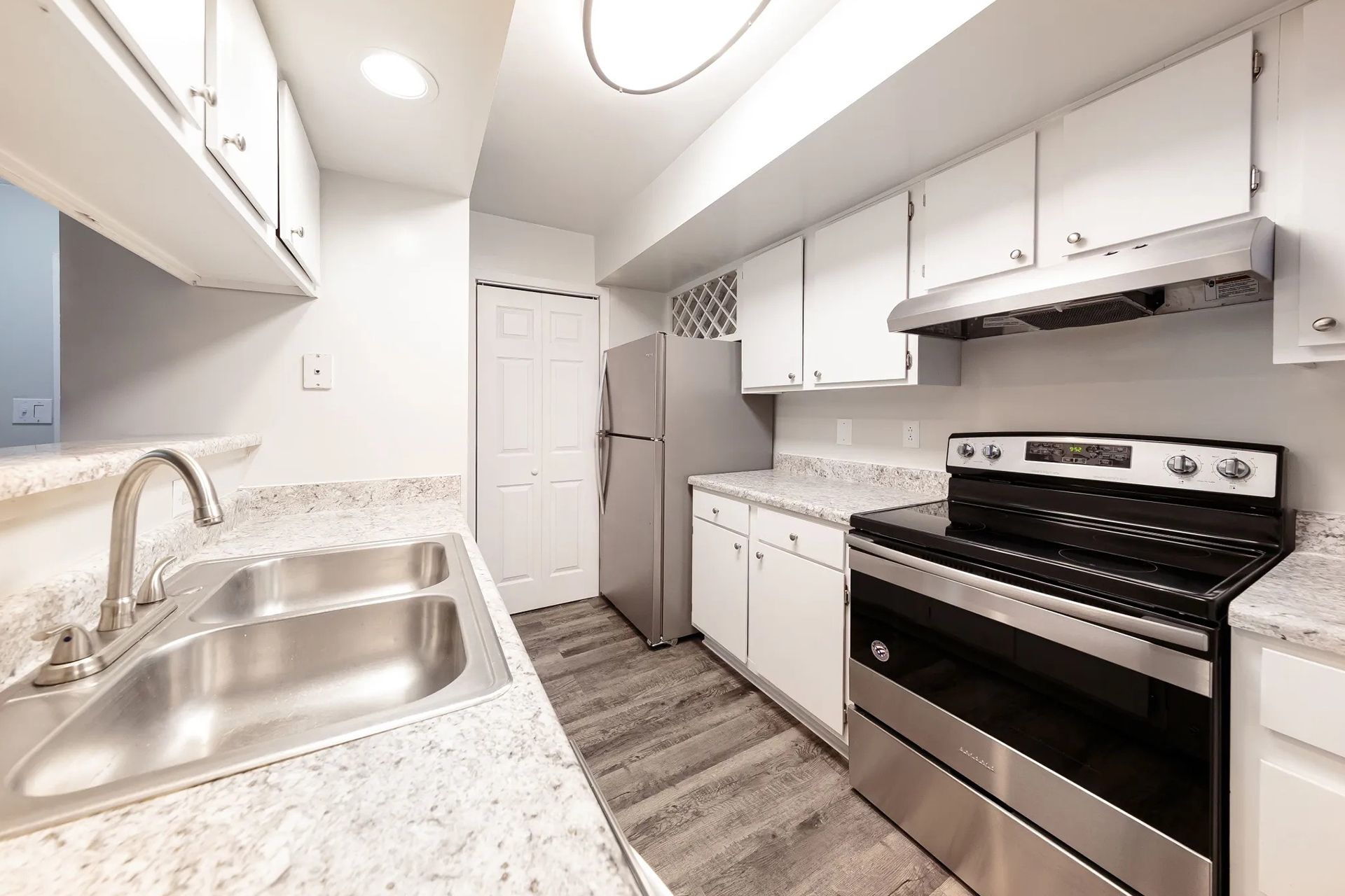 White kitchen with stainless steel appliances, countertops, and cabinets.