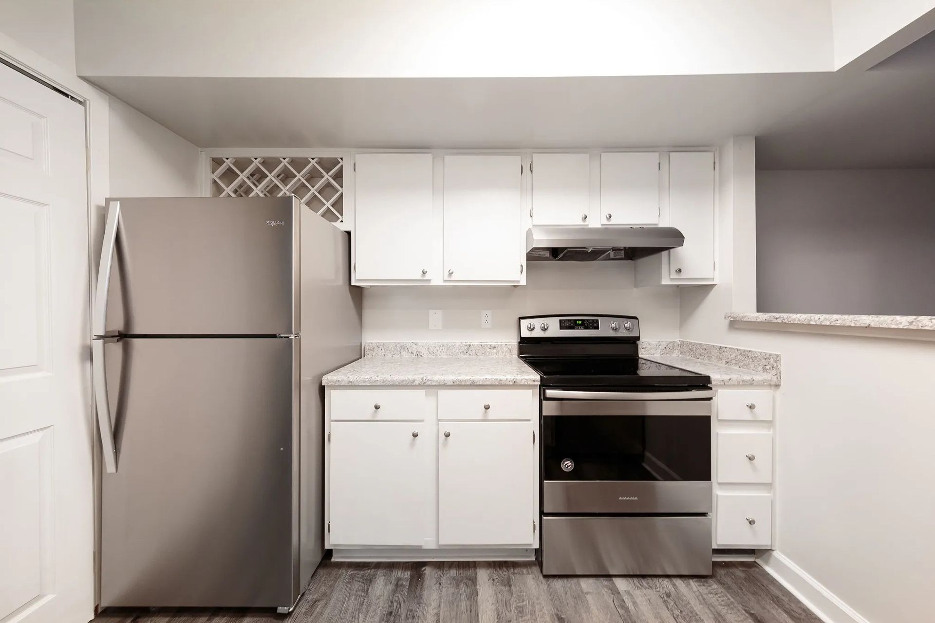 Small kitchen with stainless steel appliances, white cabinets, and gray countertop.