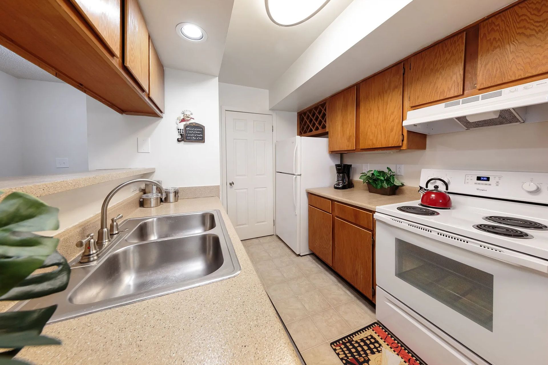 Kitchen with light-colored cabinetry and countertops, a sink, stove, and a white refrigerator.