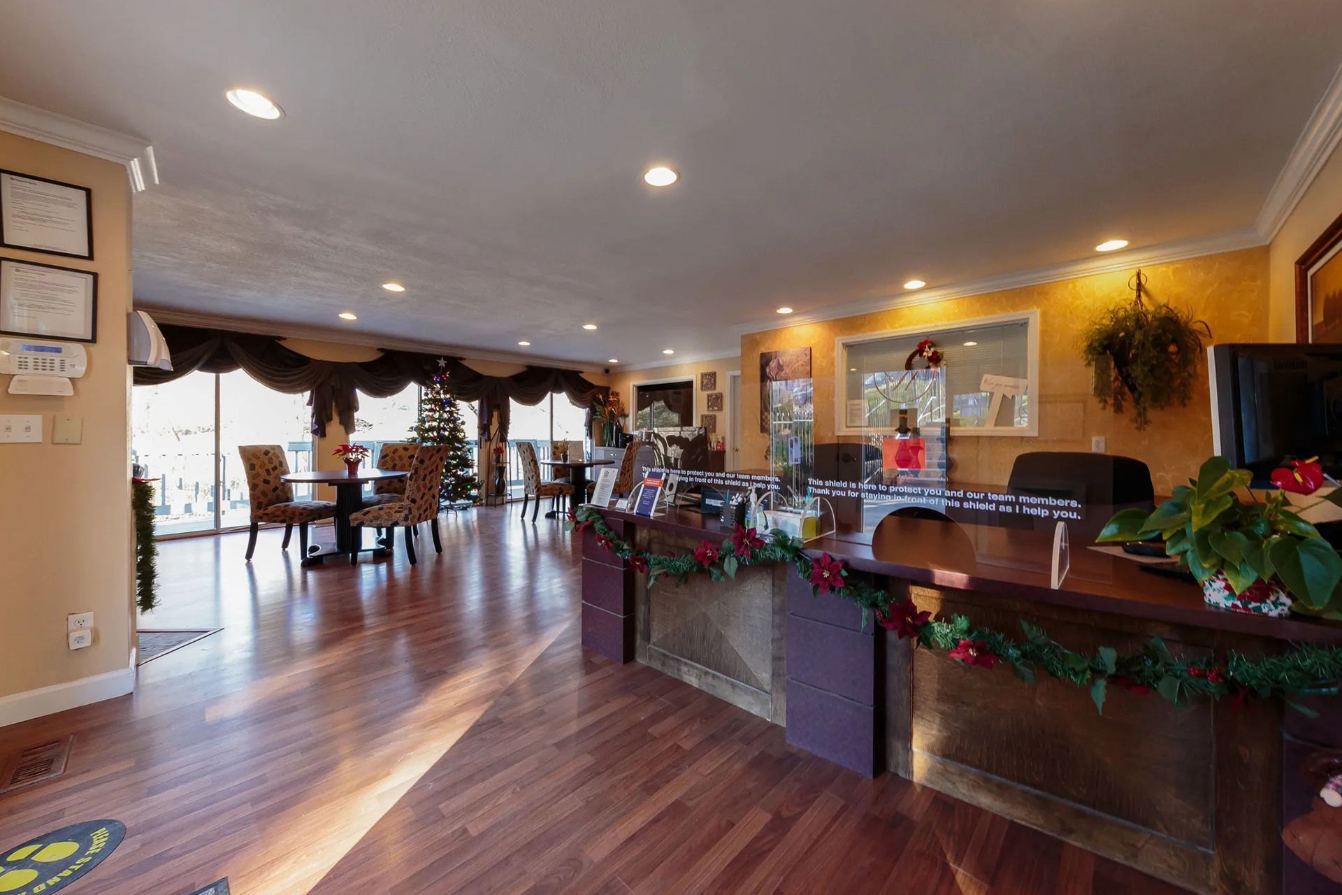 Lobby with reception desk, tables, and chairs near windows, with decorations.