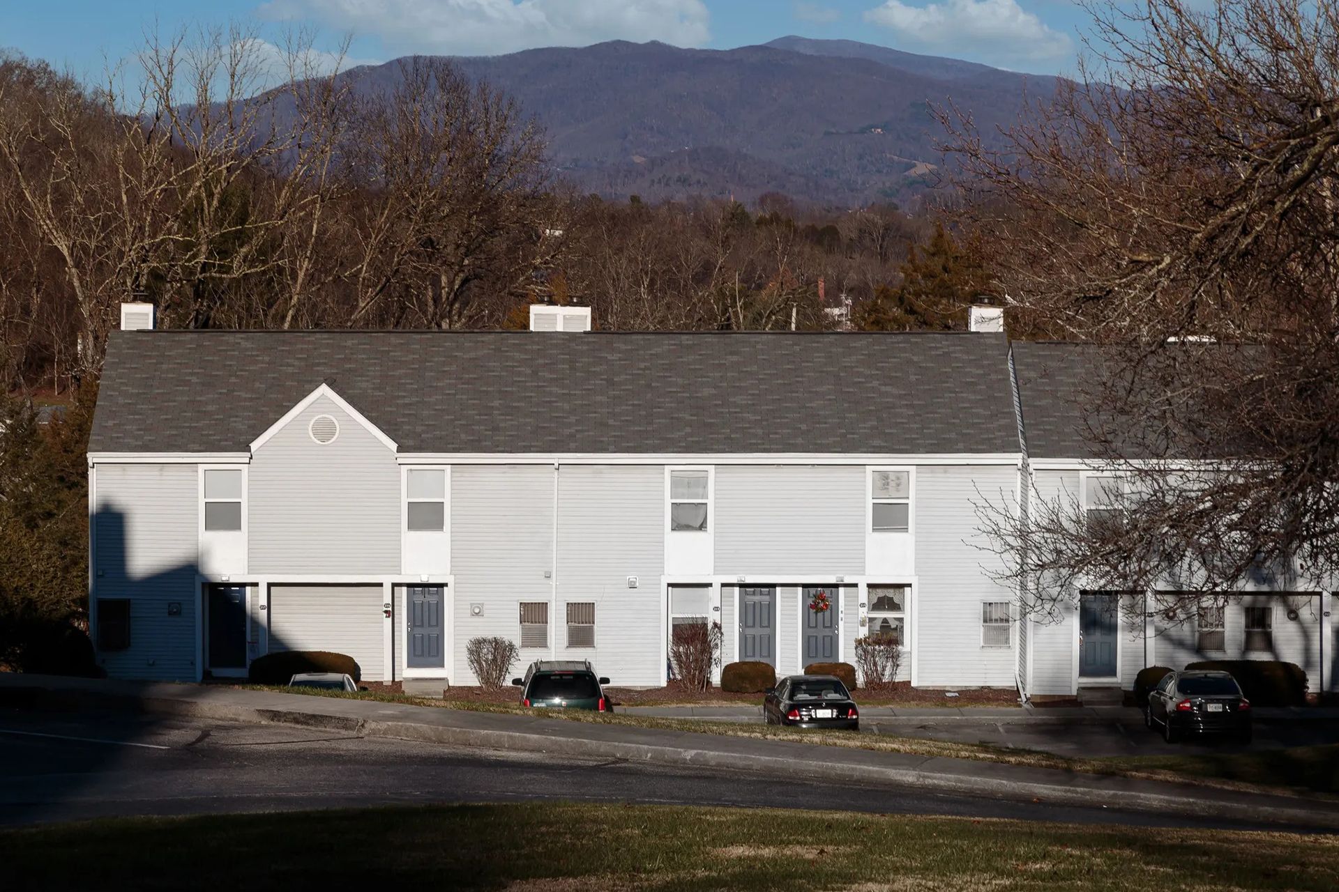 Townhouses with a mountain backdrop. Cars parked out front.