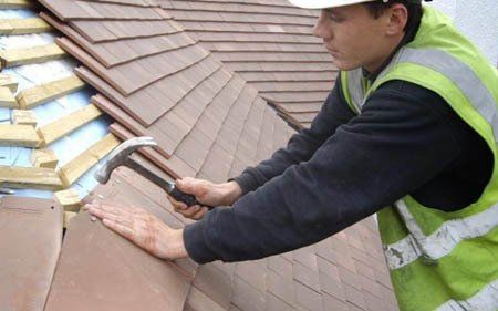 Trabajador arreglando goteras en tejado en Morón de Almazán, Soria