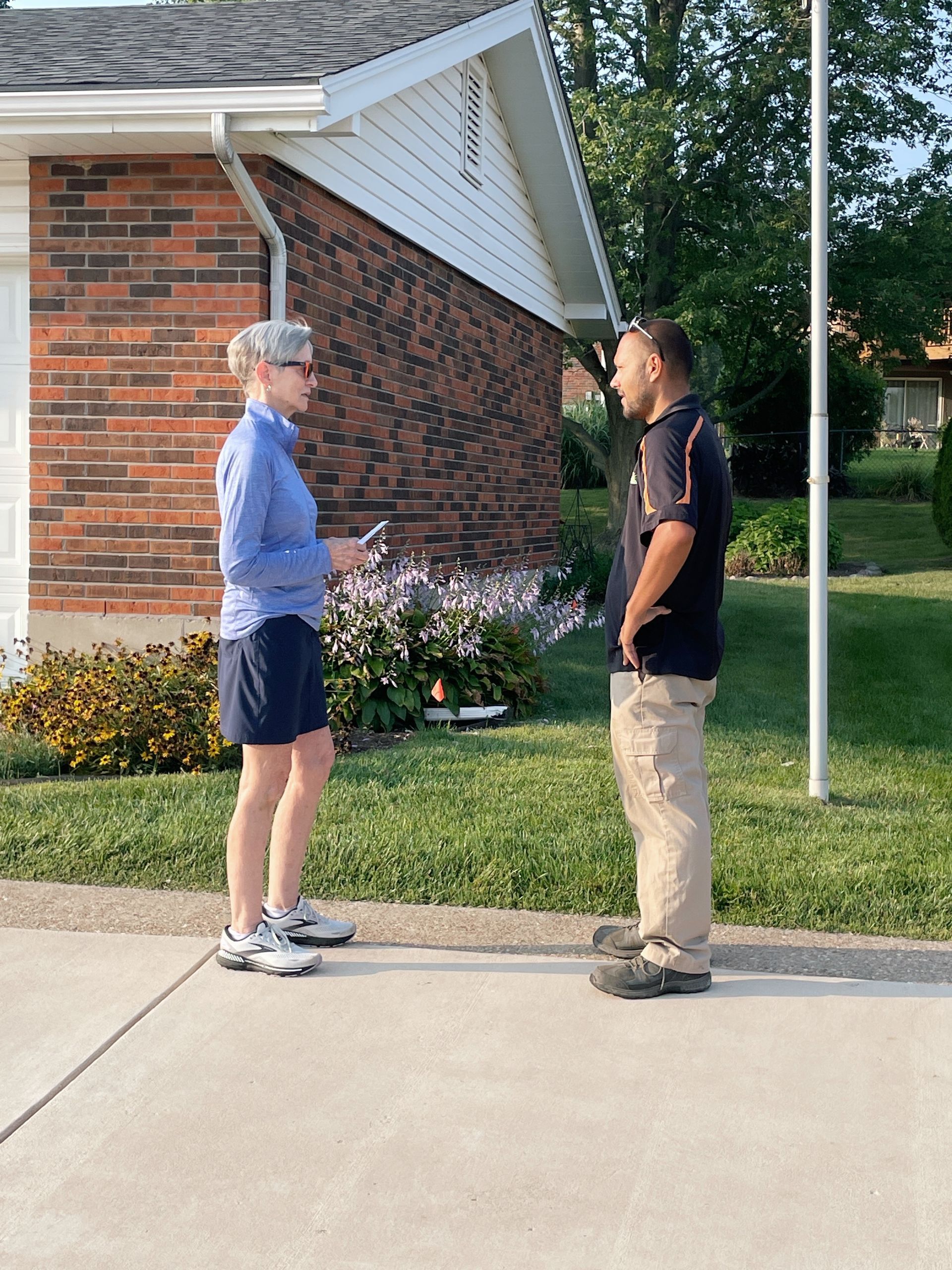 a man and a woman are standing on the sidewalk talking to each other .