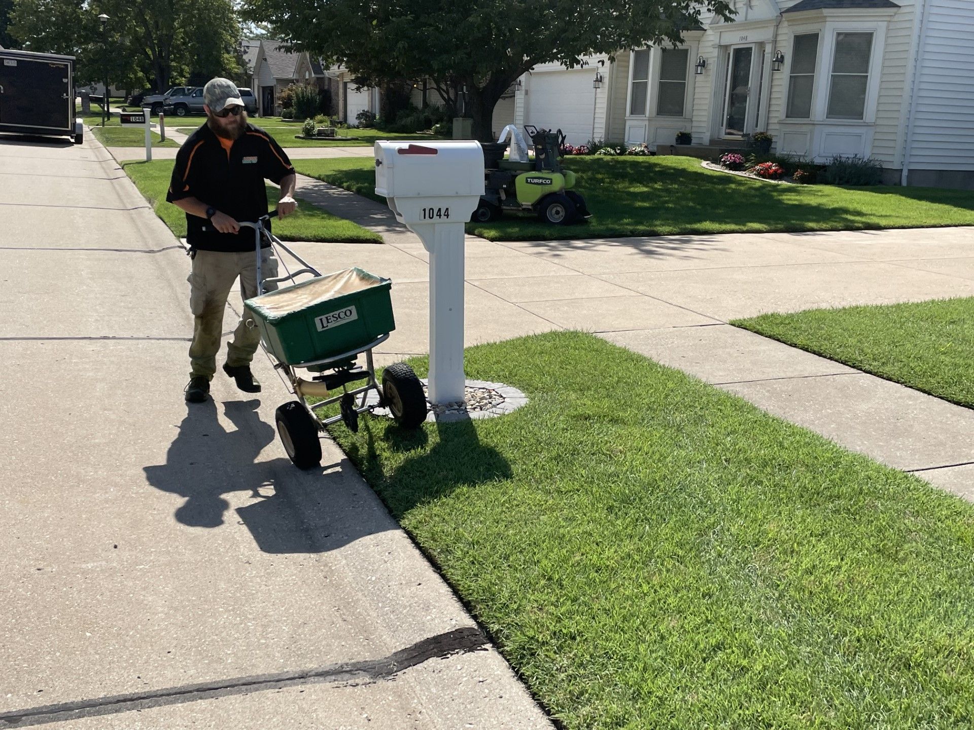 A man is walking down a sidewalk next to a mailbox
