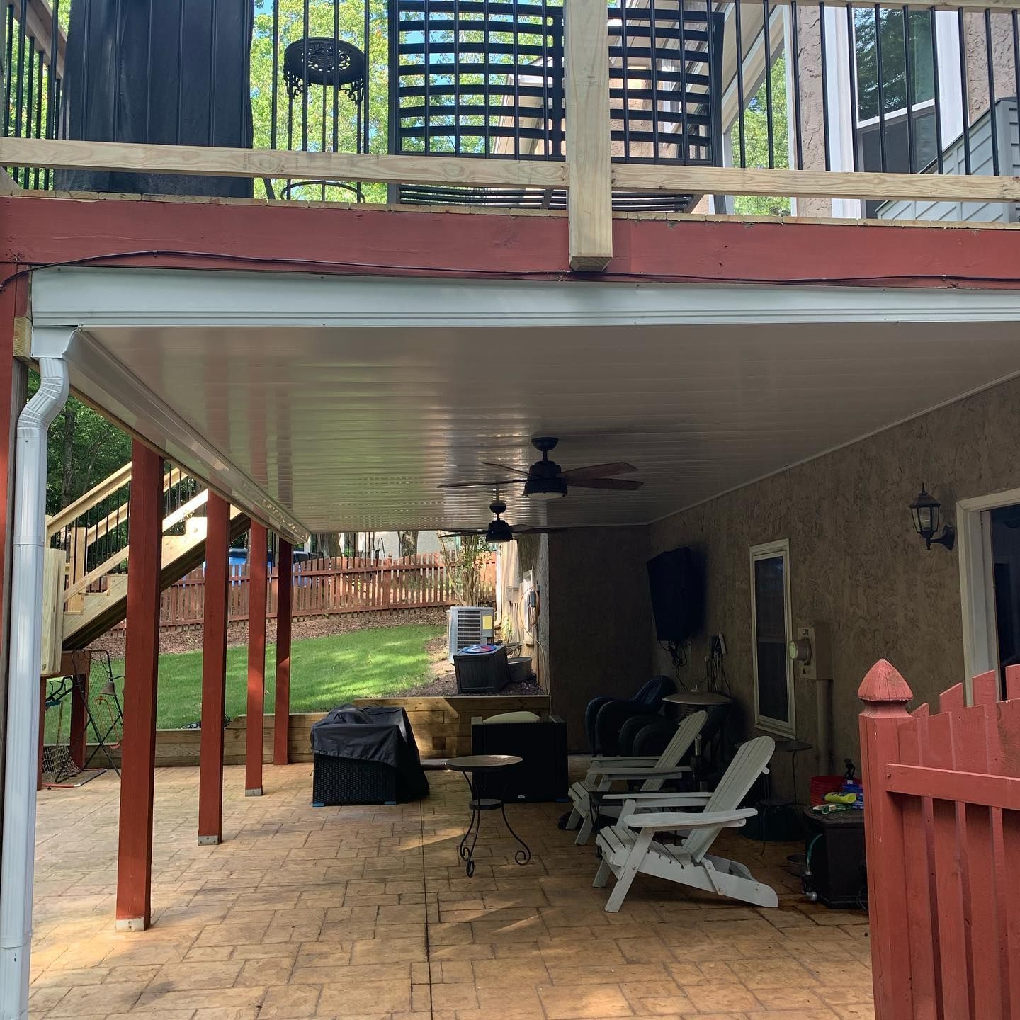 Aluminum under-deck ceiling that includes a hardscaping design, two ceiling fans, and outdoor lighting.