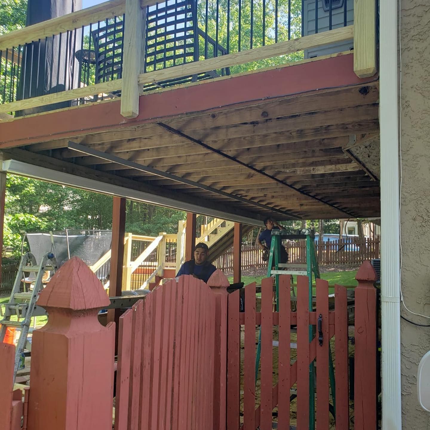 Aluminum under-deck ceiling that includes a hardscaping design, two ceiling fans, and outdoor lighting under construction.