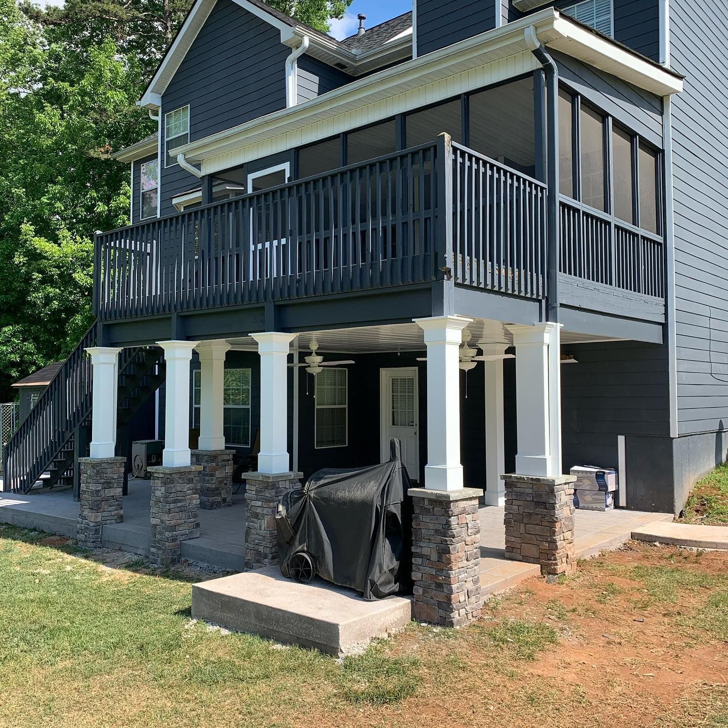 Black aluminum under-deck ceiling that includes a hardscaping design, two ceiling fans, and outdoor lighting.