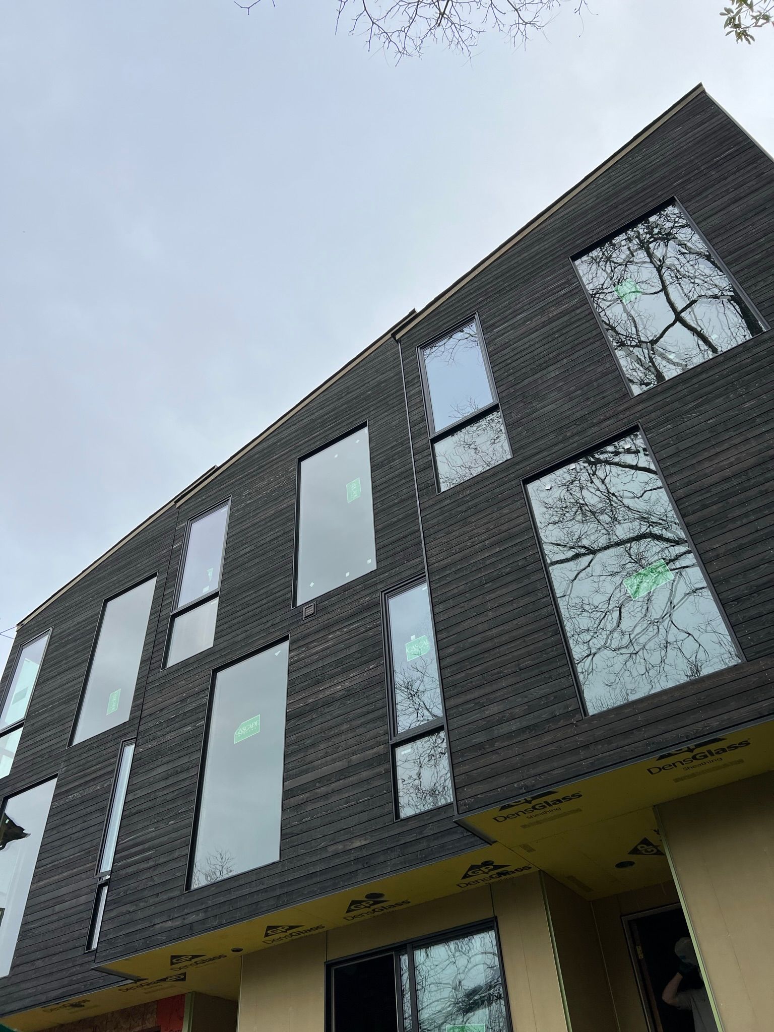 A large brick building with a lot of windows and a tree in the background.