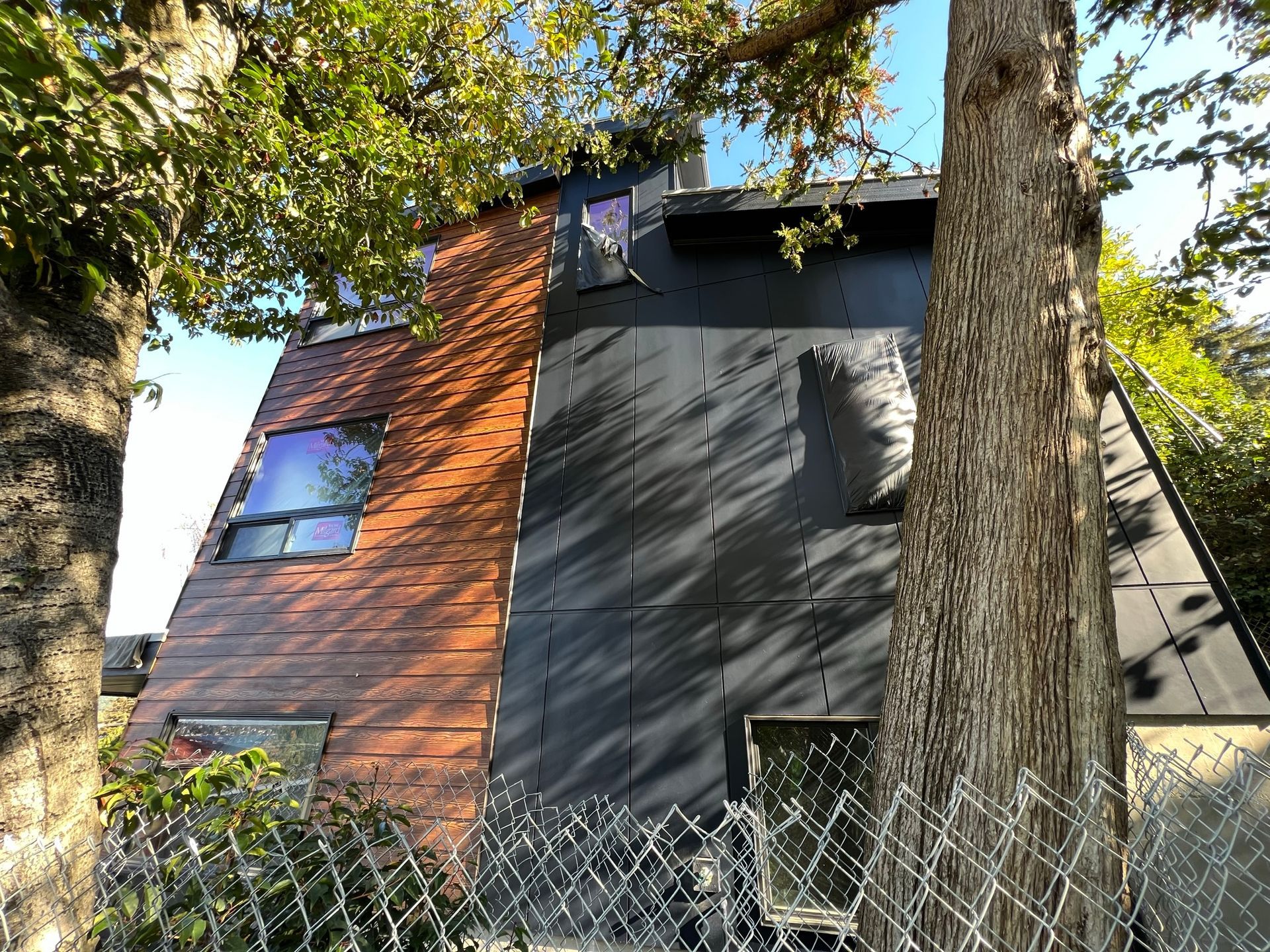 A house with a fence around it and a tree in front of it.