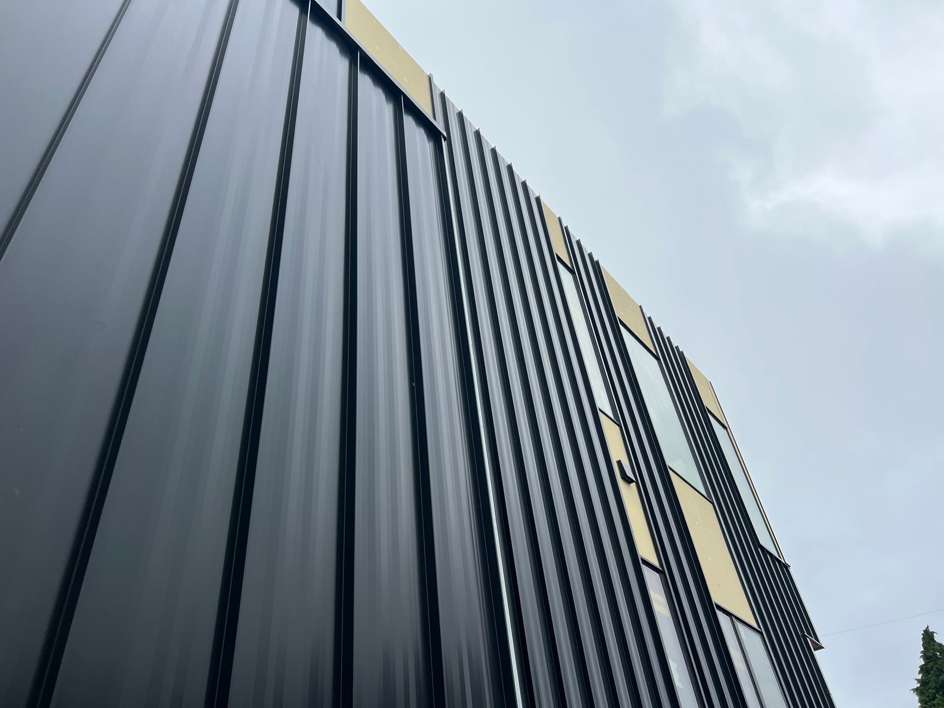 A large black building with a lot of windows and a cloudy sky in the background.