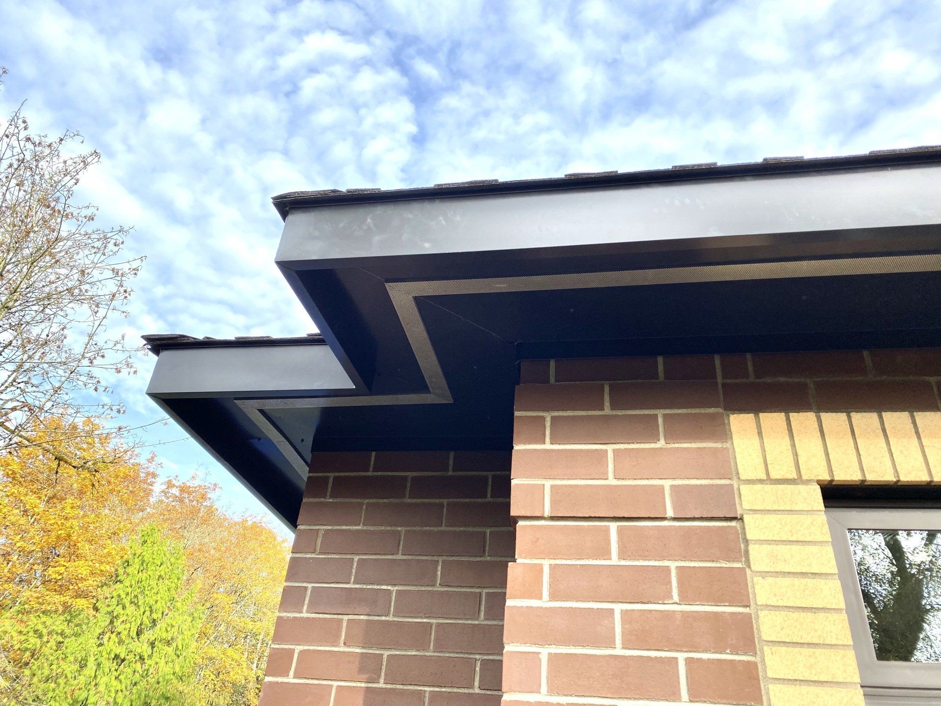 A brick building with a black roof and a window.