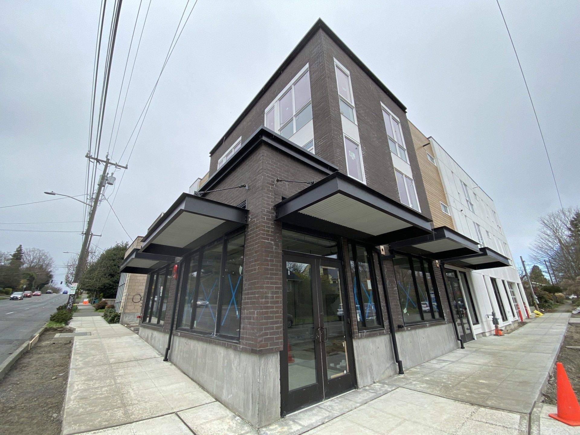 A brick building with a lot of windows is sitting on the corner of a street.