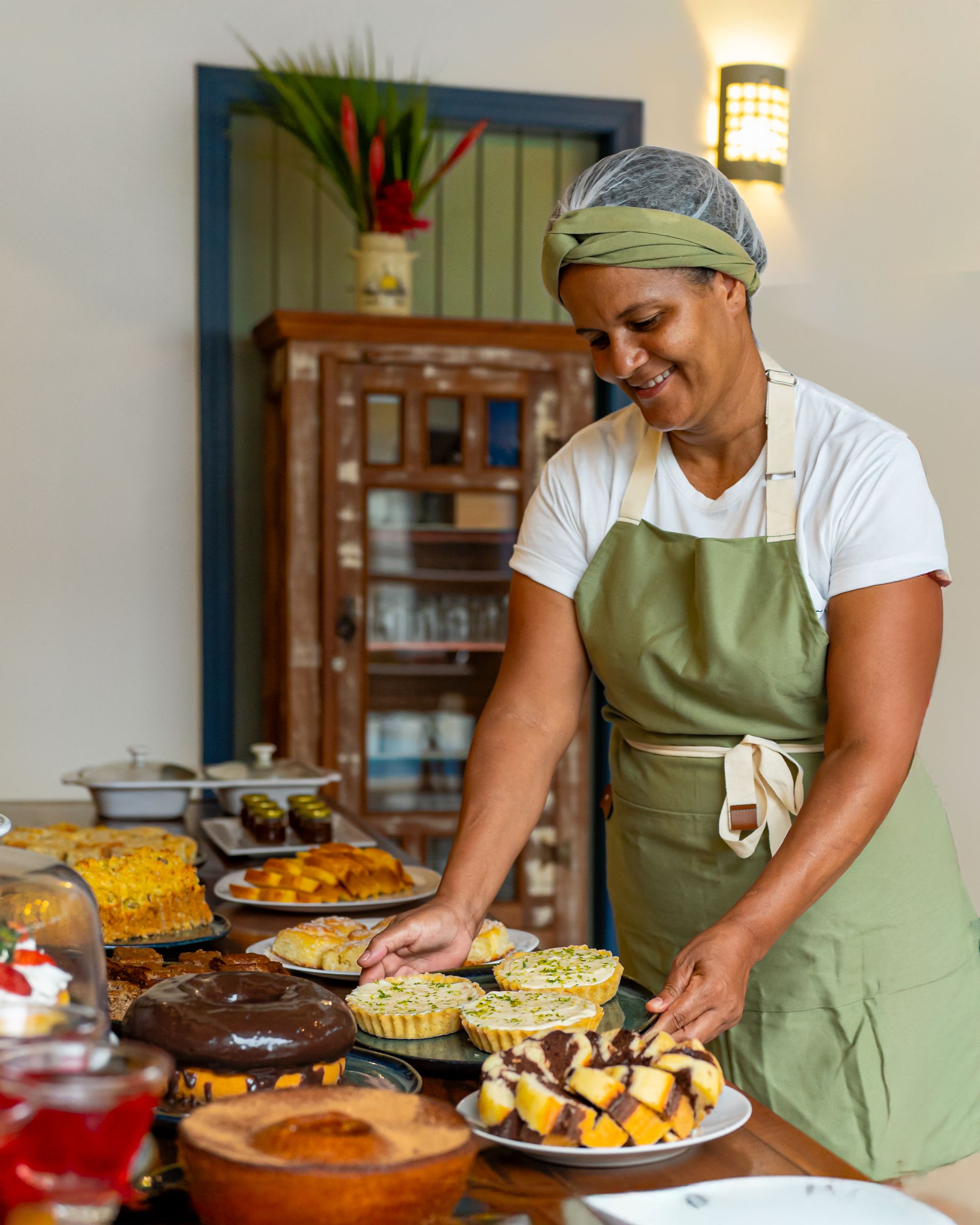 Uma mulher de avental está preparando comida em uma mesa.