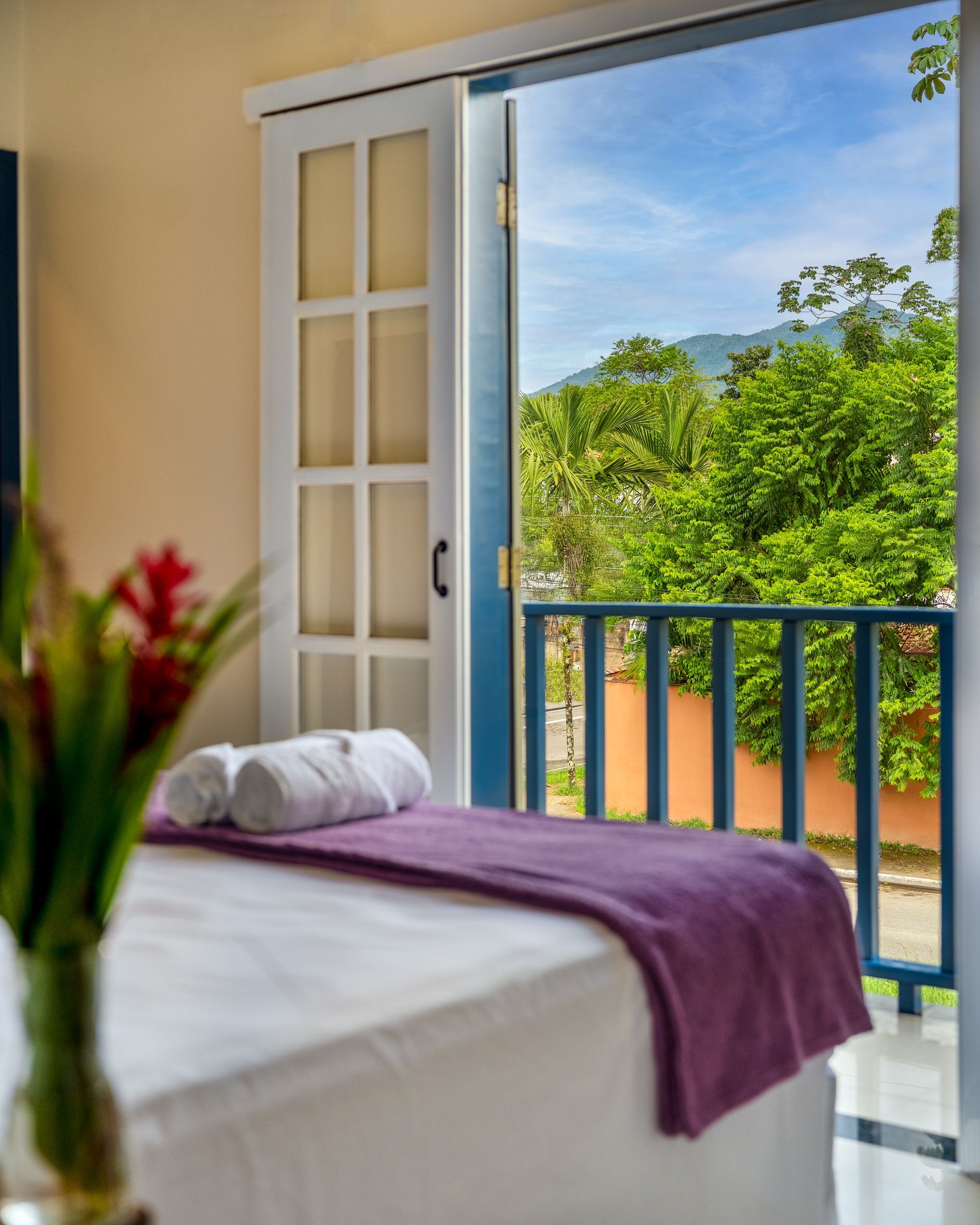 Um quarto com varanda e uma cama com um cobertor roxo