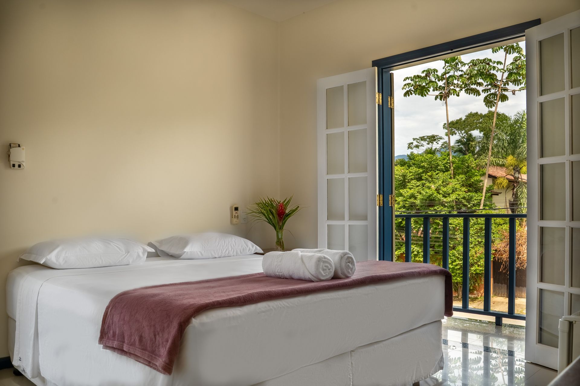 Um quarto com uma cama e uma varanda com vista para as árvores.