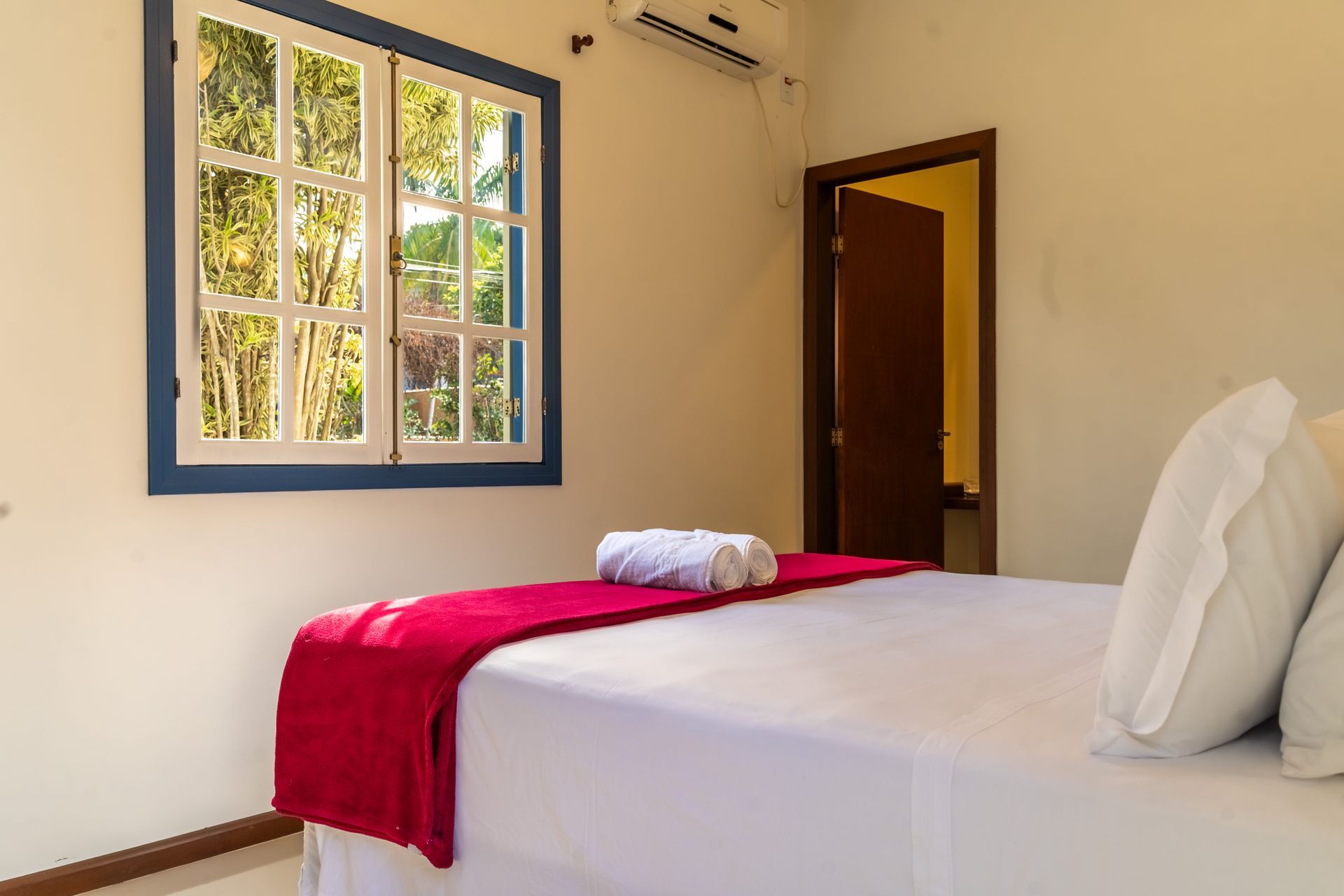 Um quarto com uma cama, janela e ar condicionado.