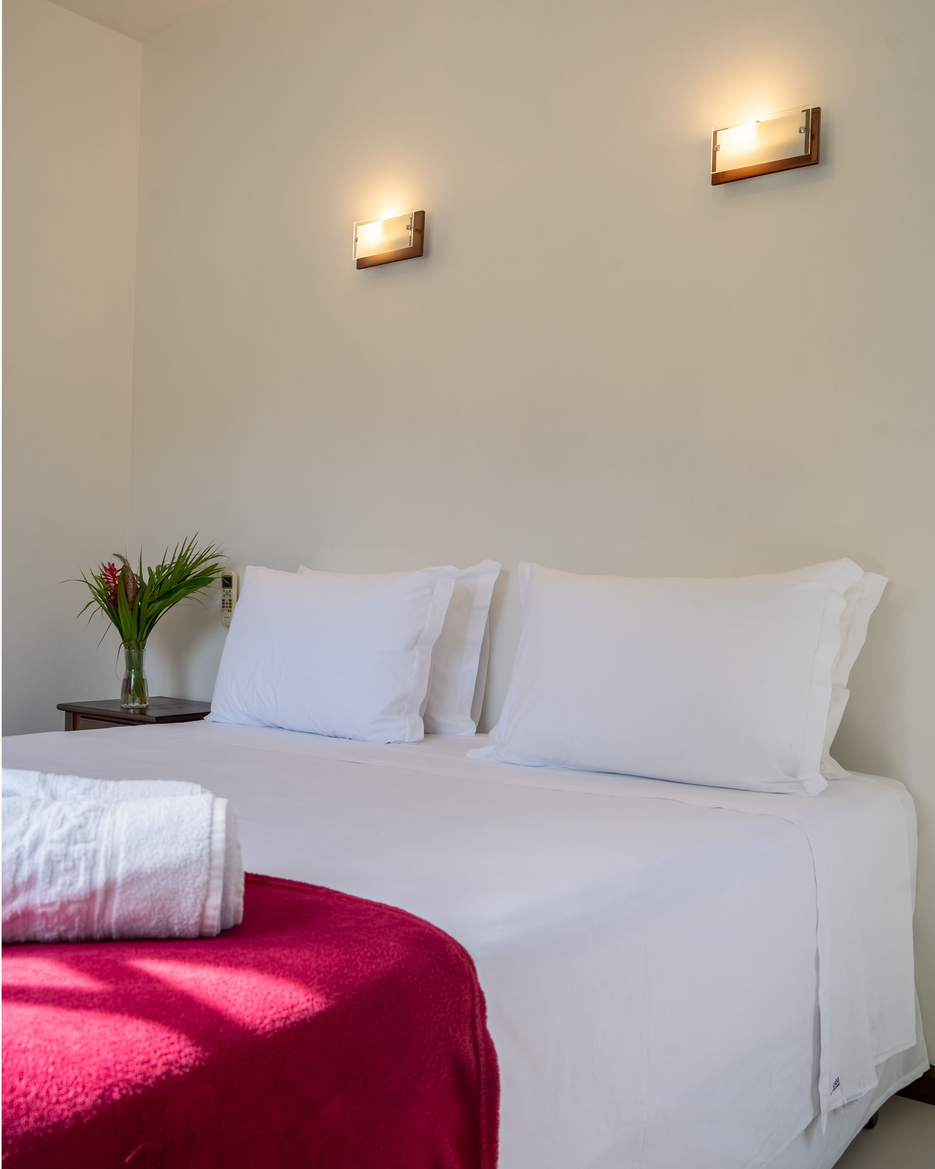 Uma cama com lençóis e travesseiros brancos em um quarto de hotel