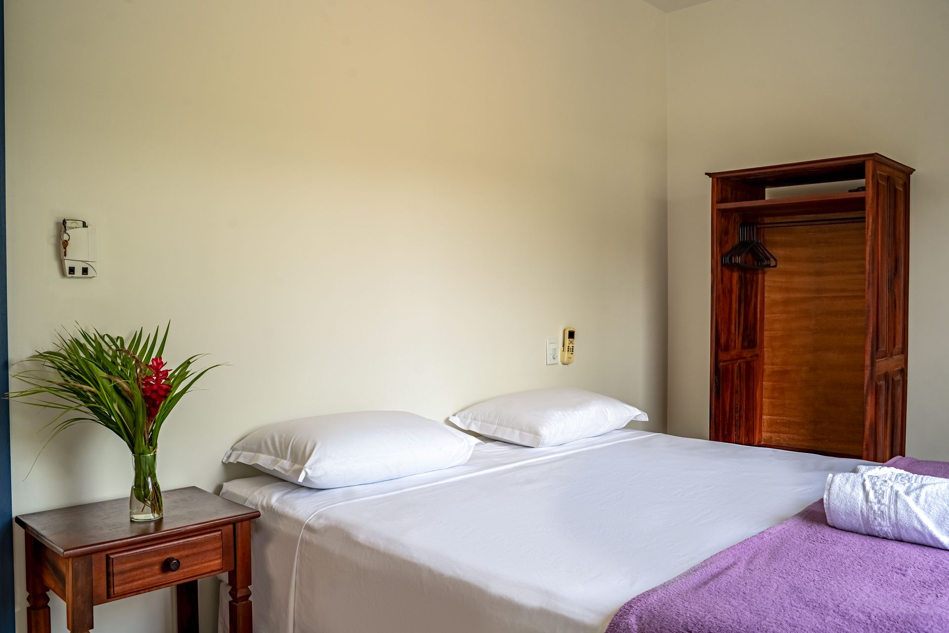 Um quarto com cama, mesa e guarda-roupa.