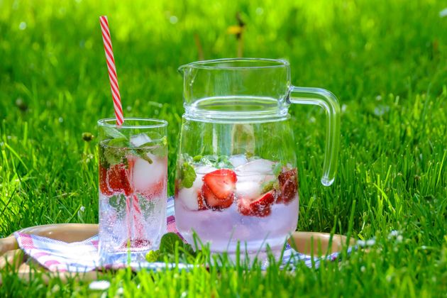 A pitcher of water with strawberries and ice cubes and a glass of water with strawberries and ice cubes.