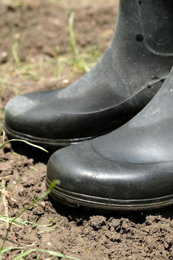 A pair of black rubber boots sitting on top of a pile of dirt.