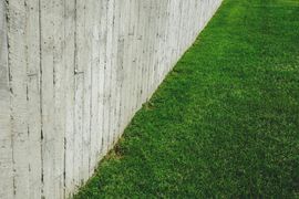 A concrete fence surrounds a lush green lawn.