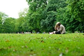 A man and a woman are sitting on the grass in a park.