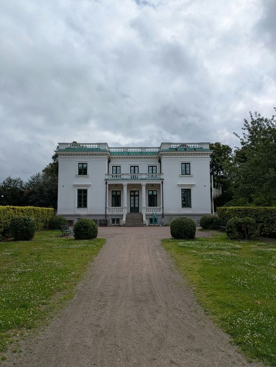 A large white house with a dirt road leading to it