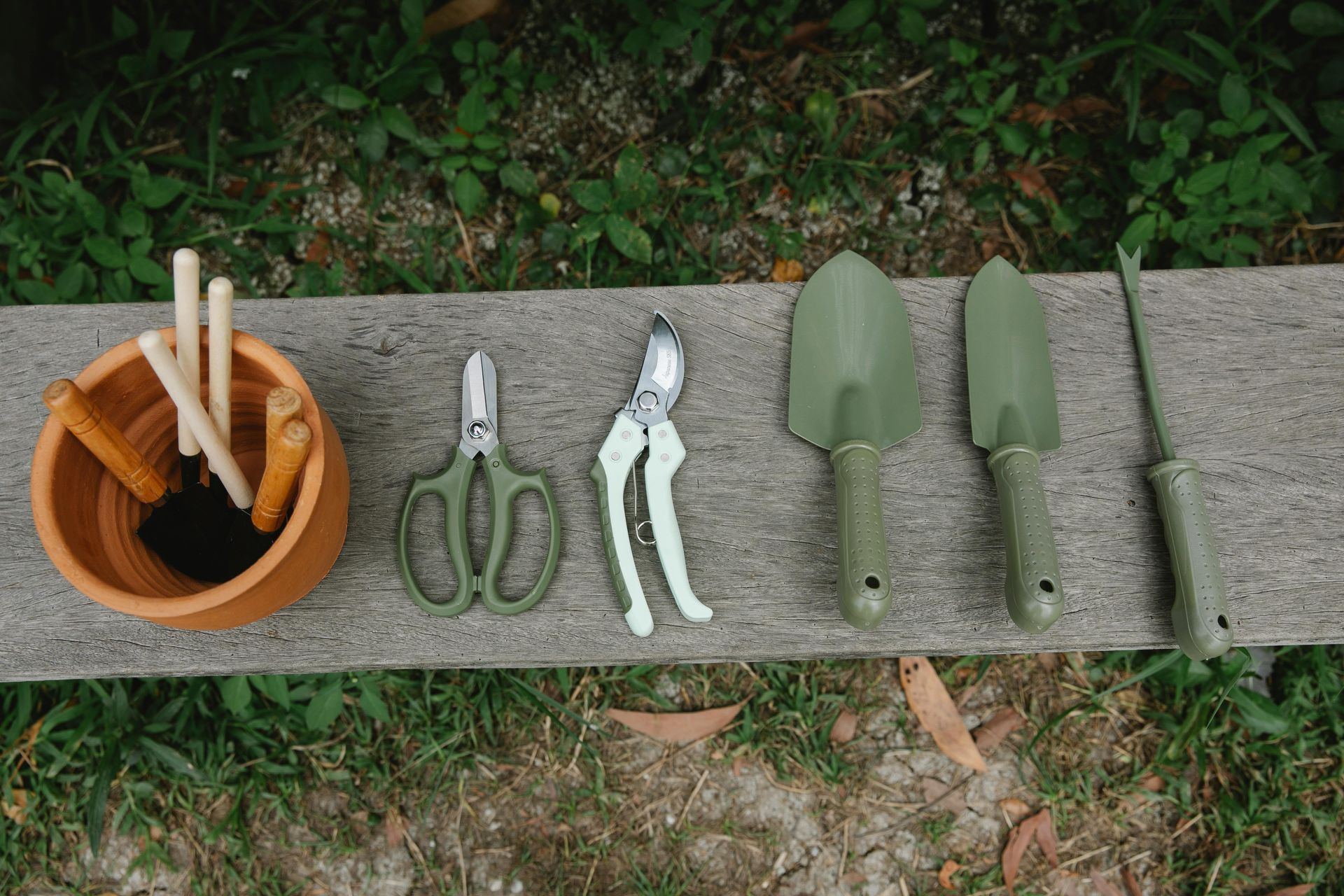 A bunch of gardening tools are sitting on a wooden bench.