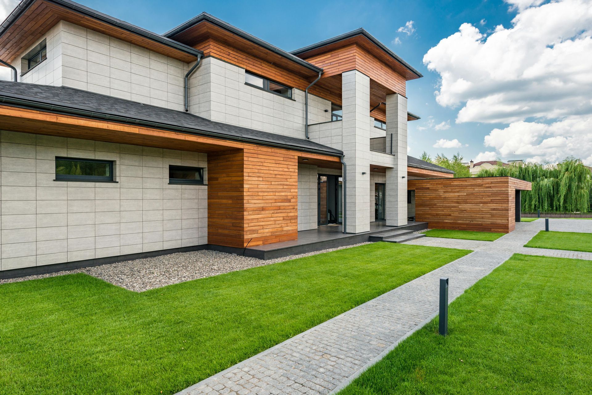 A large white and wooden house with a lush green lawn in front of it.