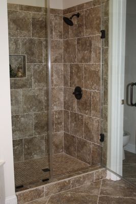 A bathroom with a walk in shower with a glass door.