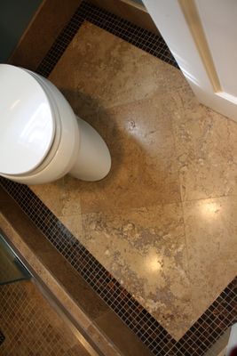 A toilet is sitting on a tiled floor in a bathroom.