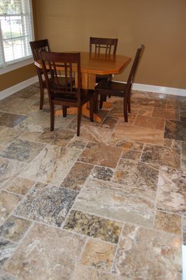 A dining room with a table and chairs on a tiled floor.