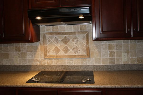 A kitchen with a stove top oven and a hood above it
