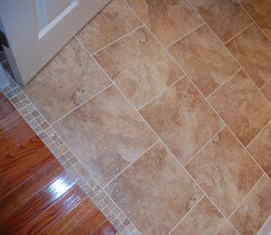 A tiled floor next to a wooden floor and a door.