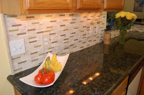 A kitchen counter with a bowl of fruit and tomatoes on it.