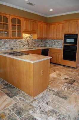 A kitchen with wooden cabinets and tile floors.