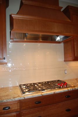 A kitchen with a stove top oven and a hood above it.