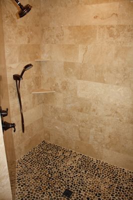 A walk in shower with a tiled floor and a shower head.
