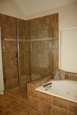 A bathroom with a walk in shower and a bathtub.