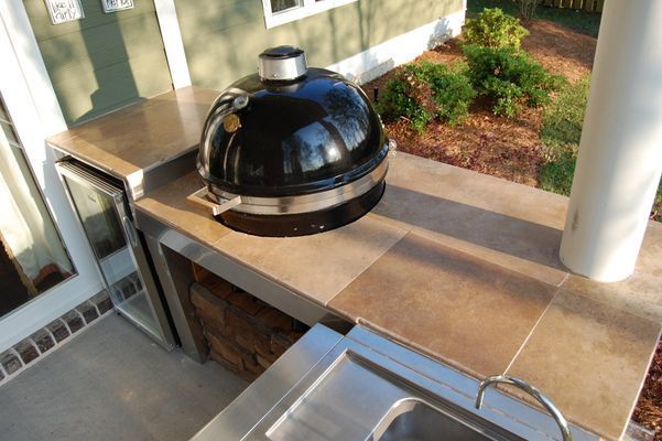 A grill is sitting on top of a counter next to a sink.