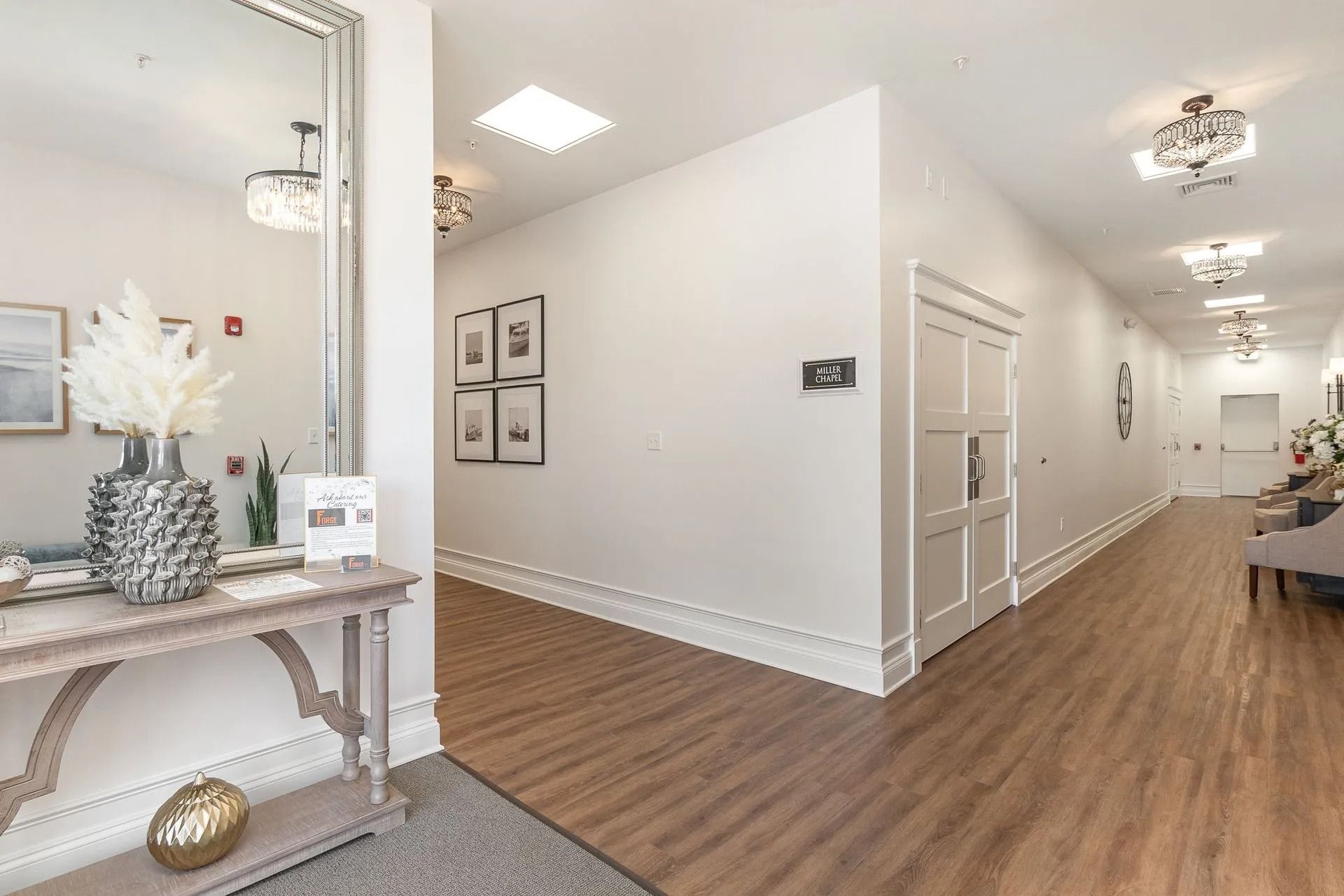 Hallway with white walls, wood floors, and decorative console table with a large mirror.