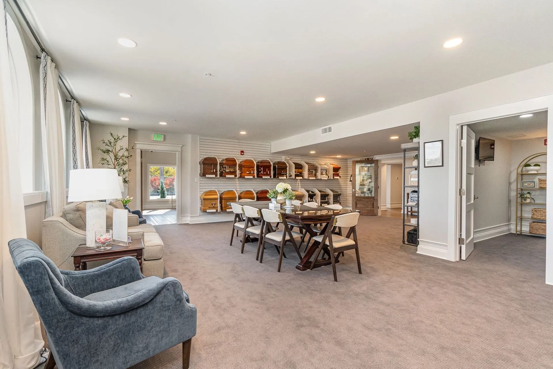 Spacious interior with seating areas, a long dining table, and art displays; neutral tones.