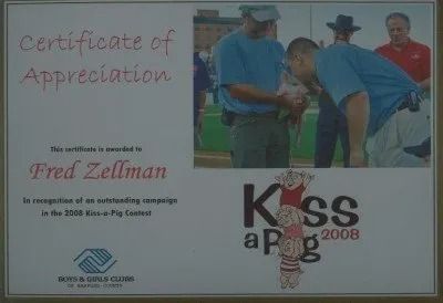 Certificate of Appreciation for Fred Zellman; he's kissing a pig at the 2008 Kiss-a-Pig contest; photo includes other men and a pig.