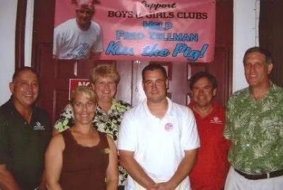 Group of people pose in front of a sign promoting a 