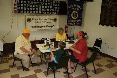 People seated around a table playing bingo in a community hall.