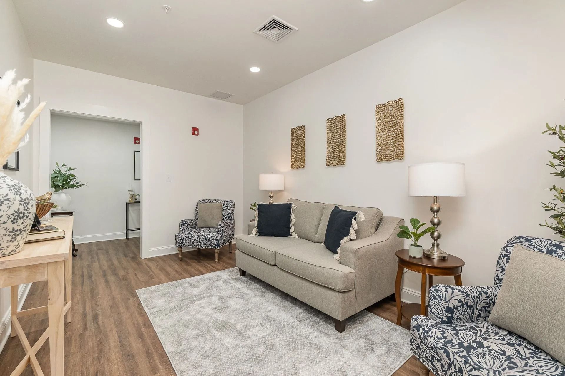 Cozy waiting room with sofa, patterned armchairs, rug, and wooden accents.