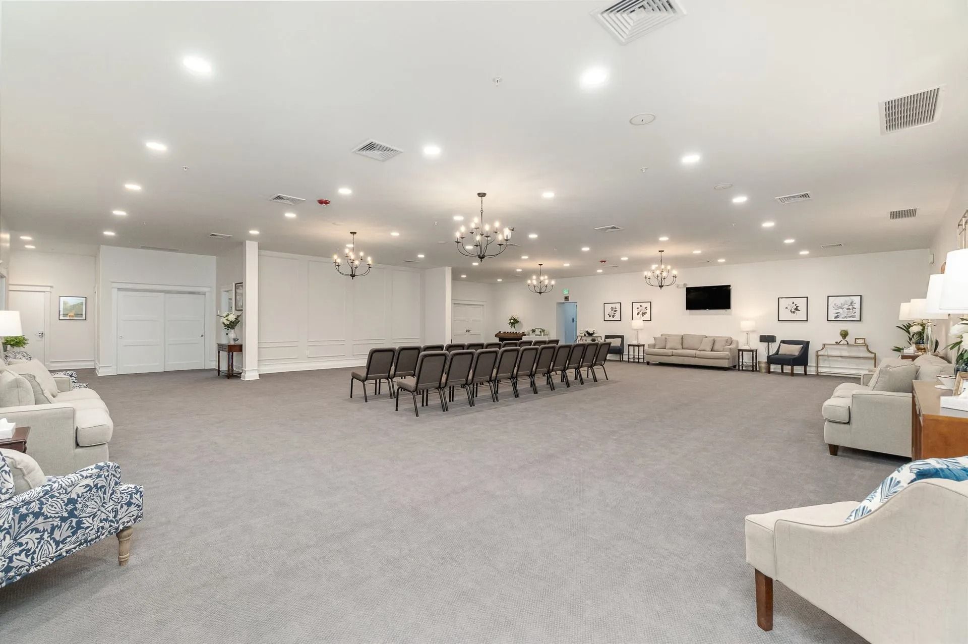 Spacious, well-lit room with chairs arranged around a table, couches, and decorative lighting.