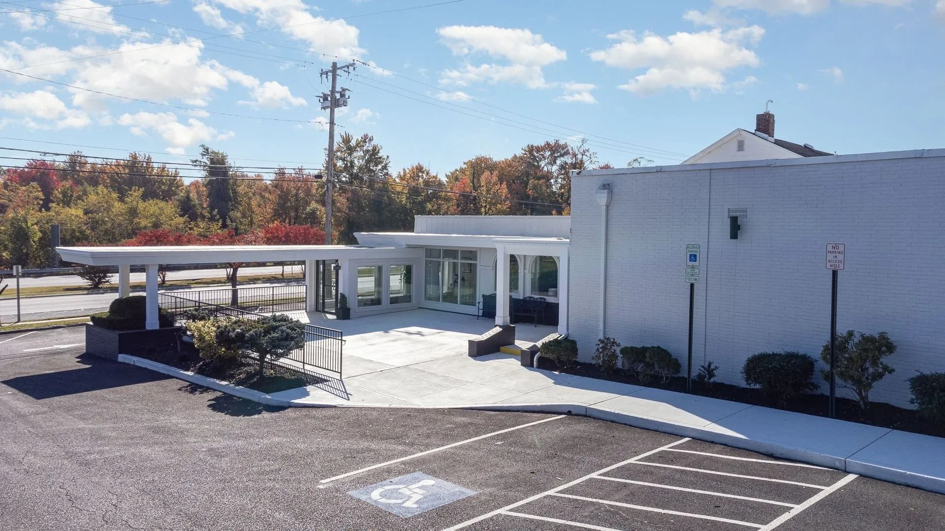 White modern building with covered entrance and parking spots, one marked for accessibility.